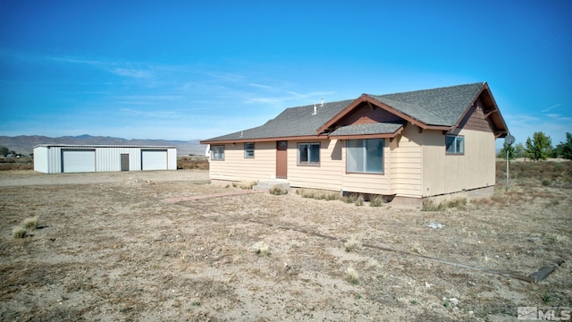 view of front facade featuring a garage, a mountain view, and an outbuilding