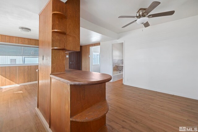 kitchen with light hardwood / wood-style flooring, ceiling fan, and wood walls