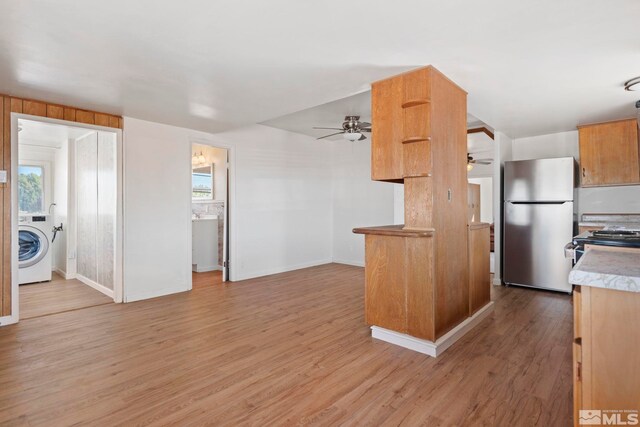 kitchen featuring washer / clothes dryer, a healthy amount of sunlight, stainless steel refrigerator, and light hardwood / wood-style flooring