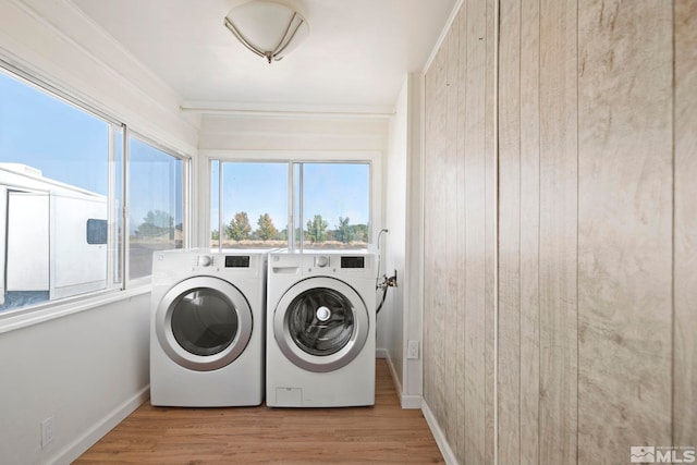 clothes washing area with ornamental molding, light hardwood / wood-style flooring, and washer and clothes dryer