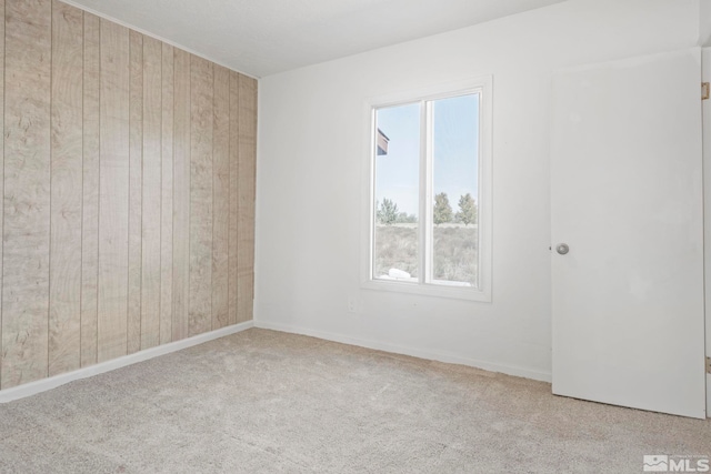 unfurnished room with light colored carpet and wooden walls