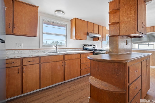 kitchen featuring sink, a center island, light wood-type flooring, and stainless steel stove