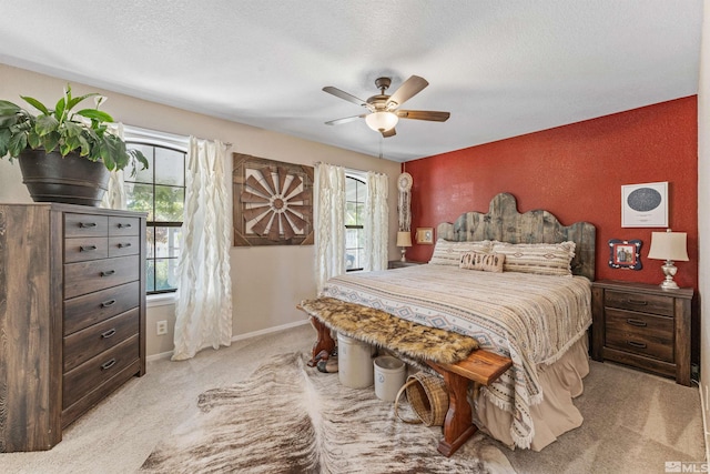 bedroom featuring light carpet, multiple windows, a textured ceiling, and ceiling fan