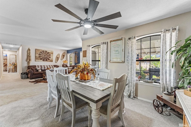 carpeted dining room featuring ceiling fan and a textured ceiling
