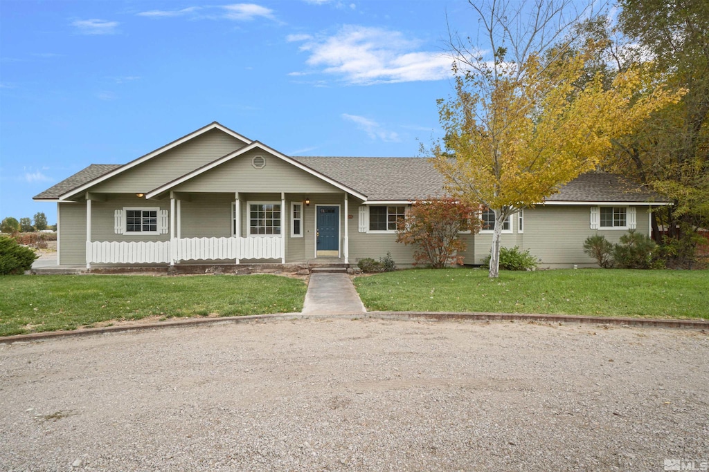 ranch-style house featuring covered porch and a front yard