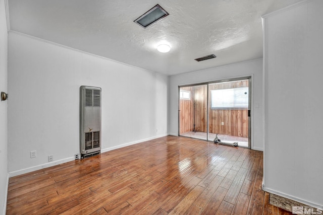 spare room featuring crown molding, hardwood / wood-style floors, and a textured ceiling