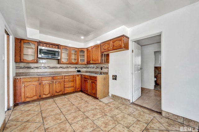 kitchen featuring sink, black electric stovetop, light tile patterned flooring, and tasteful backsplash