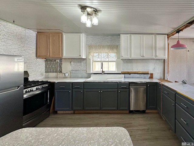 kitchen featuring gas stove, stainless steel fridge, white cabinetry, gray cabinets, and sink