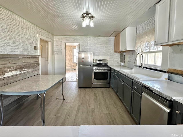 kitchen featuring white cabinets, light wood-type flooring, sink, gray cabinets, and stainless steel appliances