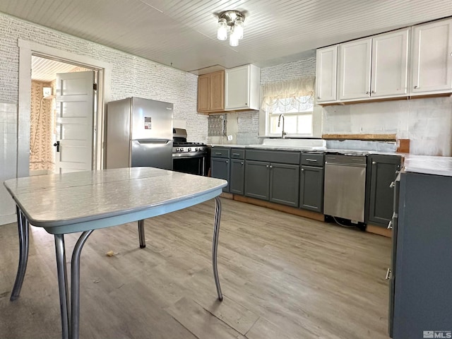 kitchen featuring white cabinetry, light wood-type flooring, sink, gray cabinets, and stainless steel appliances