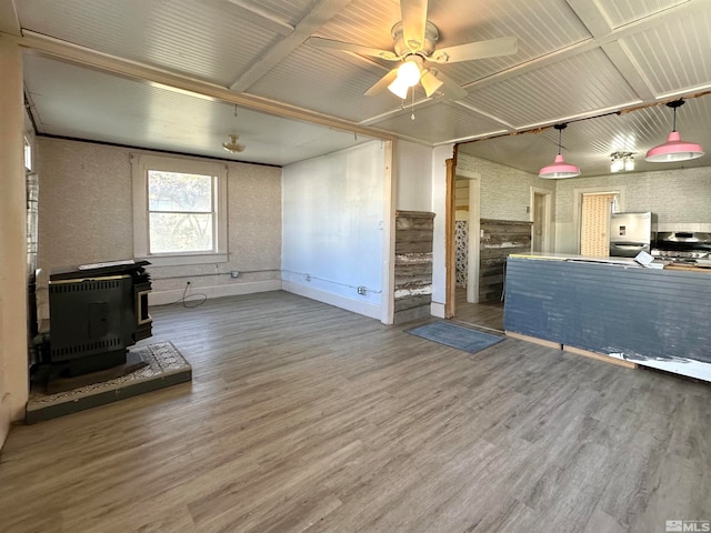 unfurnished living room featuring wood-type flooring, a wood stove, ceiling fan, heating unit, and lofted ceiling