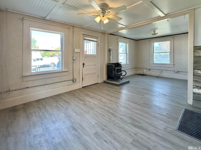 entrance foyer featuring ceiling fan, hardwood / wood-style flooring, a wood stove, and a wealth of natural light