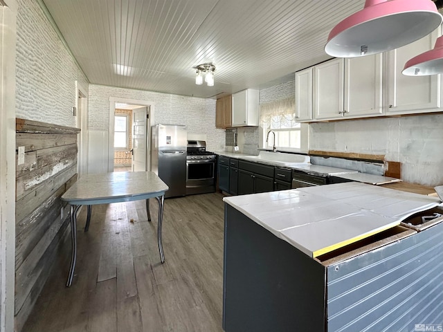 kitchen with wood-type flooring, appliances with stainless steel finishes, sink, and white cabinets