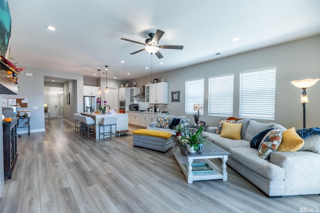 living room with light hardwood / wood-style floors, sink, and ceiling fan