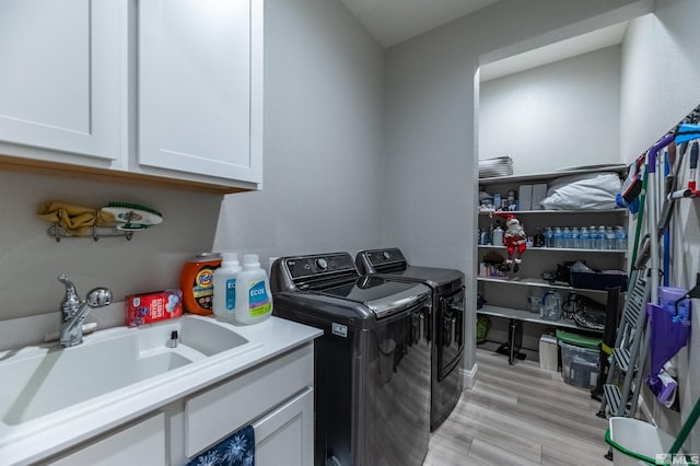 laundry room with sink, independent washer and dryer, light hardwood / wood-style floors, and cabinets