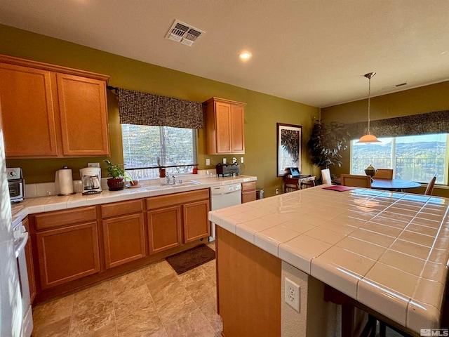 kitchen with tile countertops, dishwasher, sink, and hanging light fixtures