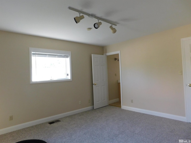 carpeted empty room featuring track lighting