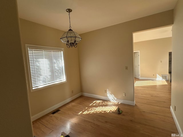 spare room featuring light hardwood / wood-style floors and an inviting chandelier