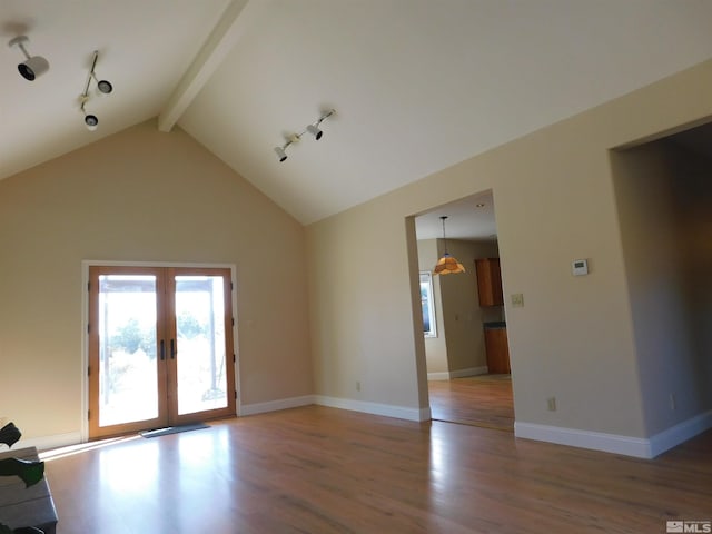 unfurnished room with hardwood / wood-style floors, rail lighting, high vaulted ceiling, beamed ceiling, and french doors