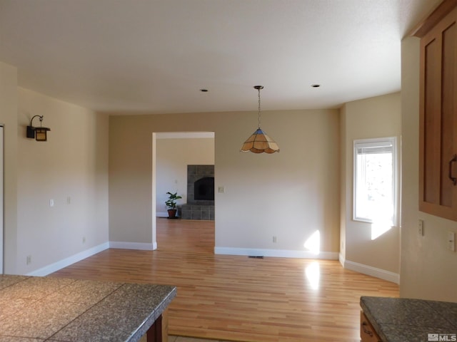 kitchen with light hardwood / wood-style flooring, hanging light fixtures, and a fireplace