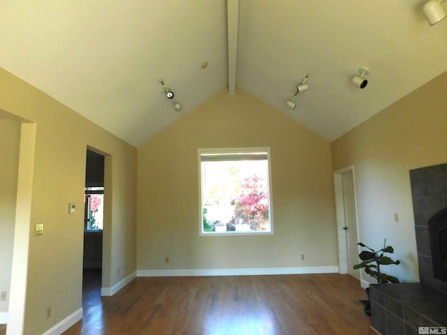 unfurnished living room featuring dark wood-type flooring, lofted ceiling with beams, and rail lighting