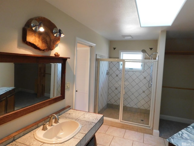 bathroom featuring vanity, a skylight, a shower with shower door, and tile patterned flooring