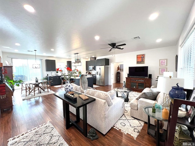 living room featuring ceiling fan, dark hardwood / wood-style flooring, and a textured ceiling