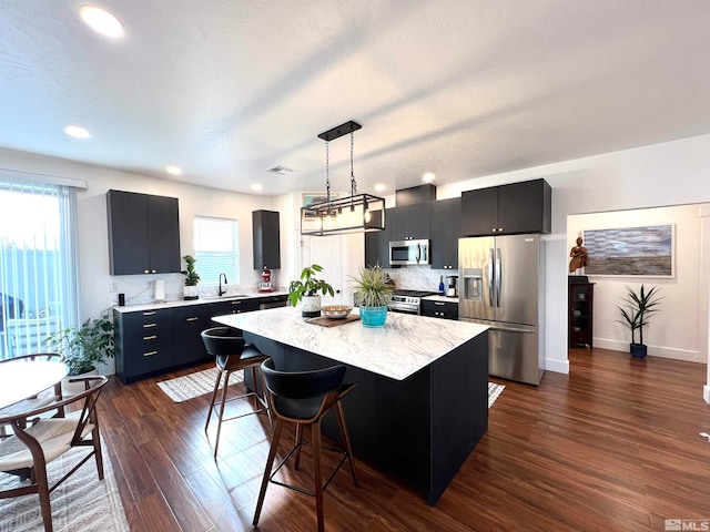 kitchen with pendant lighting, a center island, decorative backsplash, stainless steel appliances, and dark hardwood / wood-style flooring