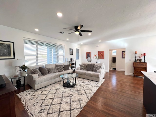 living room with ceiling fan, dark wood-type flooring, and a textured ceiling