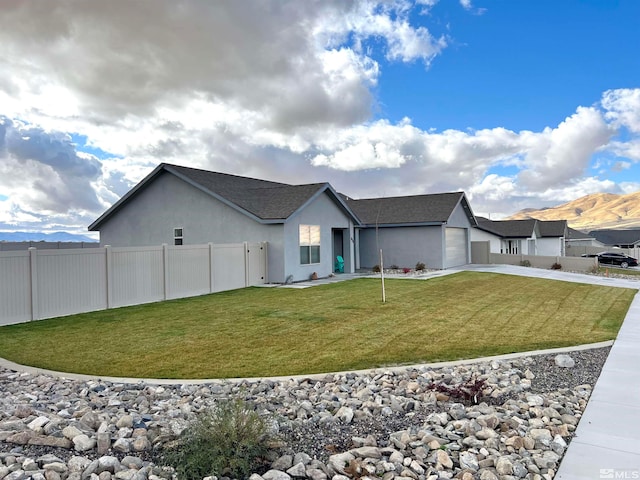 exterior space featuring a front lawn, a garage, and a mountain view