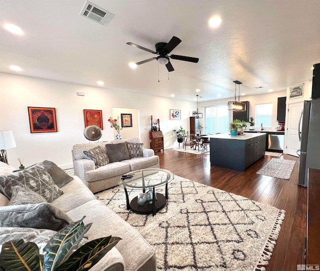 living room with a textured ceiling, ceiling fan, and dark hardwood / wood-style floors