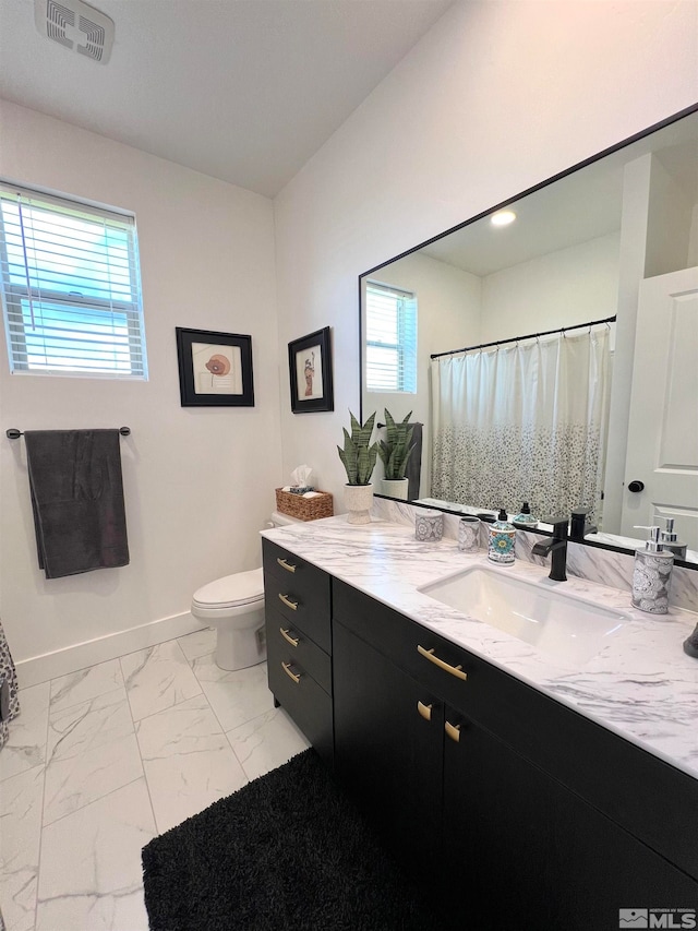 bathroom with toilet, vanity, and plenty of natural light