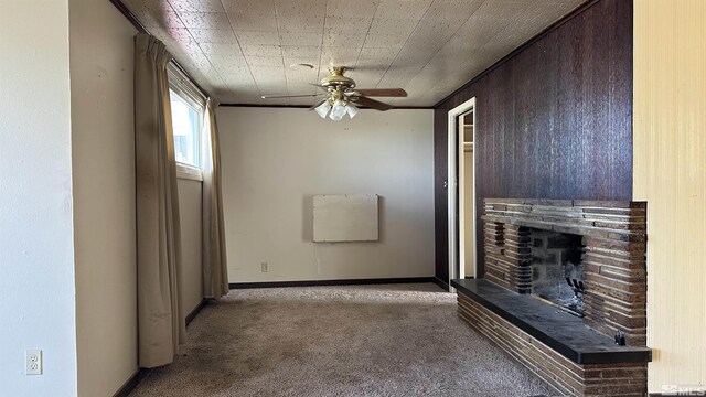 unfurnished living room featuring carpet flooring, a fireplace with raised hearth, ceiling fan, and baseboards