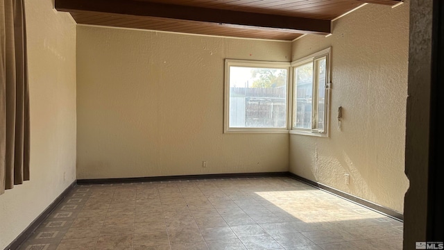 unfurnished room with wooden ceiling and beamed ceiling