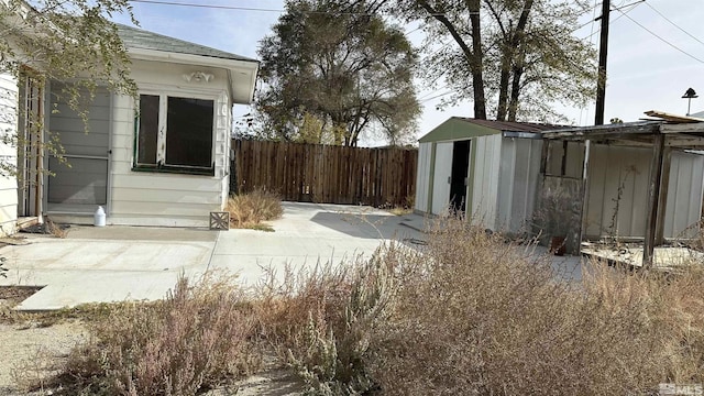 view of yard featuring an outdoor structure, a patio, fence, and a shed