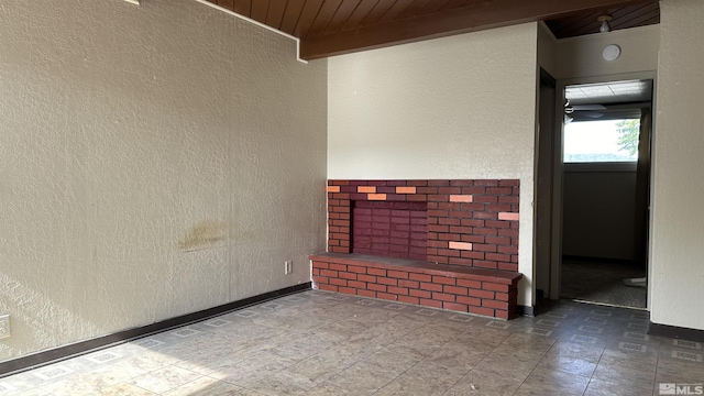 unfurnished room with a textured wall, wooden ceiling, and baseboards
