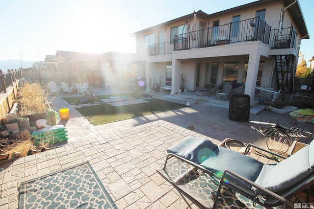 rear view of house featuring a patio, a balcony, and a swimming pool