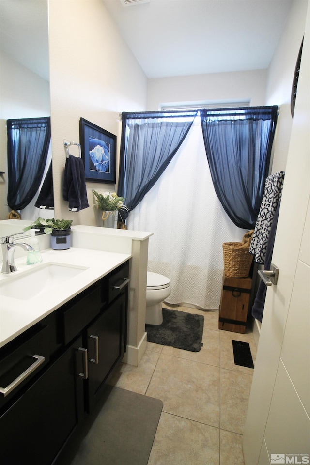 bathroom with vanity, toilet, lofted ceiling, and tile patterned flooring