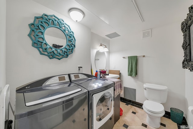 bathroom featuring vanity, washing machine and dryer, toilet, and tile patterned flooring