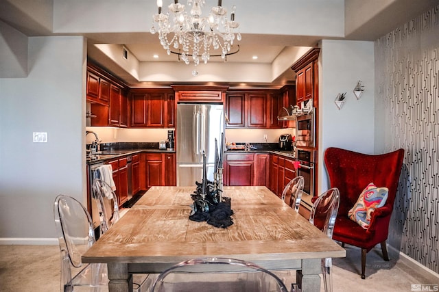 kitchen with appliances with stainless steel finishes, sink, hanging light fixtures, light carpet, and a chandelier