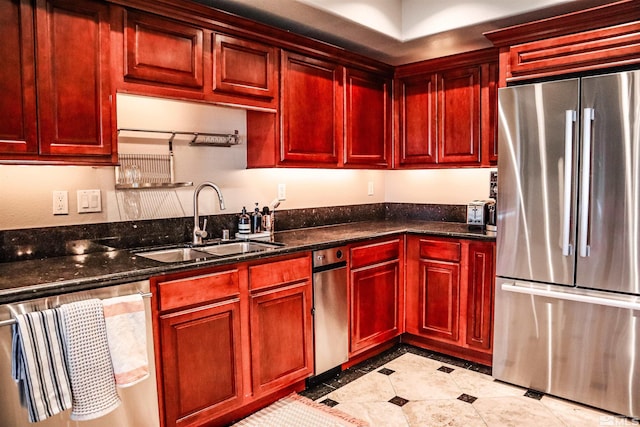 kitchen featuring appliances with stainless steel finishes, sink, and dark stone counters