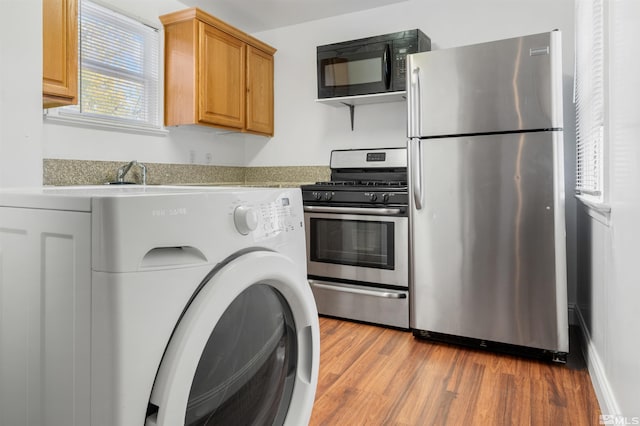 kitchen featuring stainless steel appliances, light hardwood / wood-style floors, and washer / clothes dryer