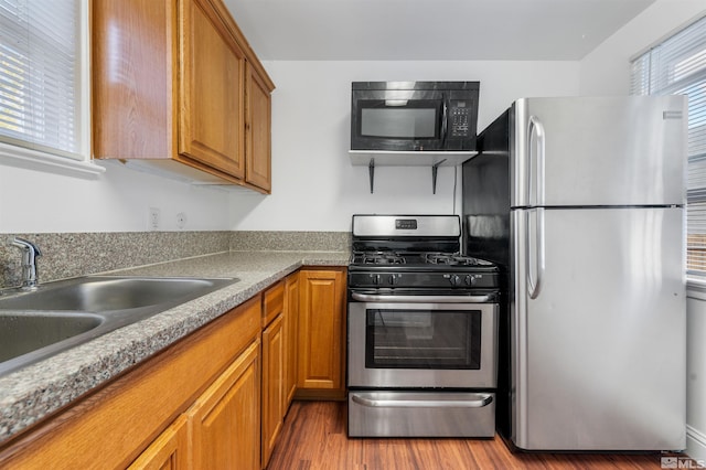 kitchen featuring appliances with stainless steel finishes, sink, and light hardwood / wood-style floors