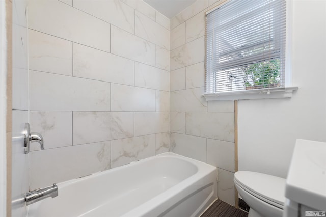 bathroom featuring tiled shower / bath and toilet