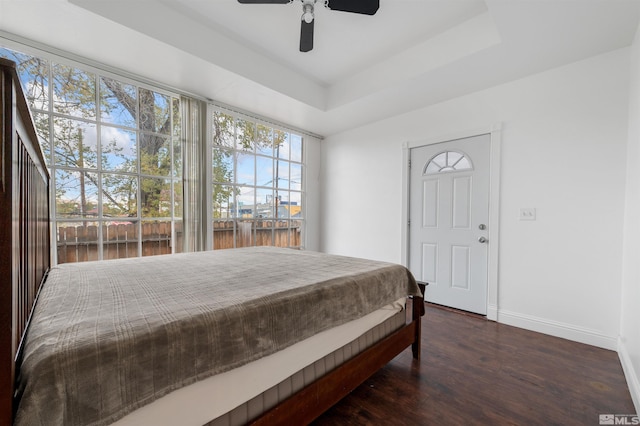 bedroom featuring dark hardwood / wood-style floors, a tray ceiling, and ceiling fan