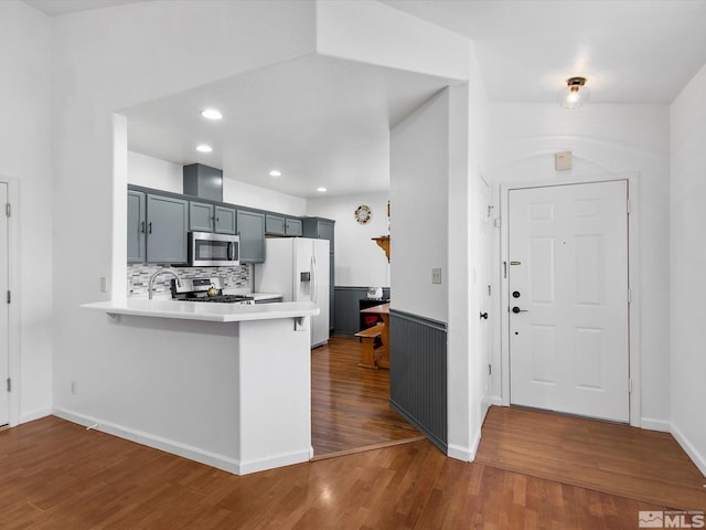 kitchen with tasteful backsplash, a kitchen bar, dark hardwood / wood-style flooring, kitchen peninsula, and stainless steel appliances