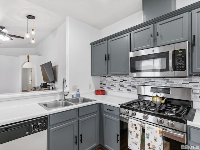 kitchen featuring hanging light fixtures, backsplash, sink, gray cabinetry, and stainless steel appliances