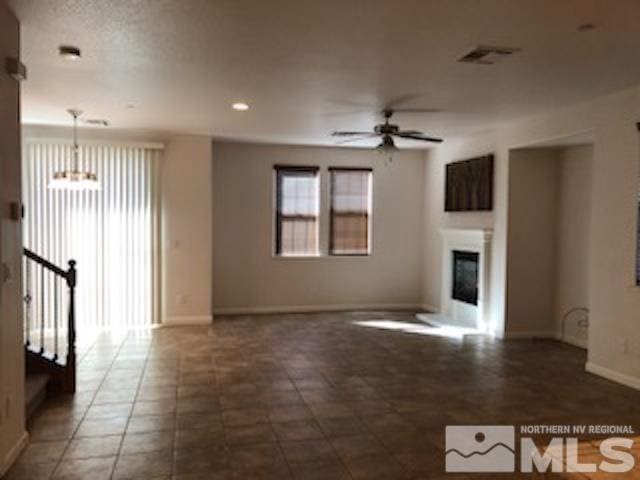 unfurnished living room featuring dark tile patterned floors and ceiling fan