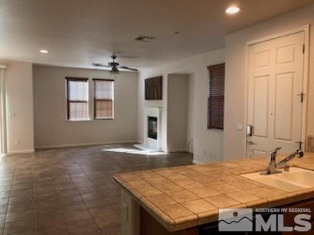 kitchen featuring tile countertops, dark tile patterned flooring, sink, and ceiling fan