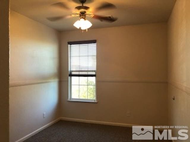 unfurnished room with ceiling fan and dark carpet